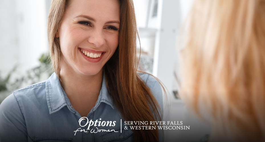 Smiling young woman talking with a caring woman in a cozy space at Options for Women – River Falls