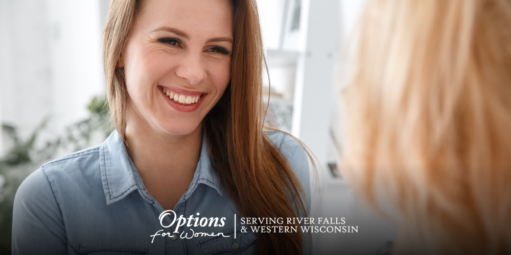 Smiling young woman talking with a caring woman in a cozy space at Options for Women – River Falls